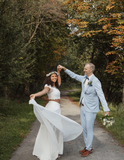 Brautpaar tanzt auf einem Waldweg im Herbst, Hochzeit am Jagdschloss Mönchbruch